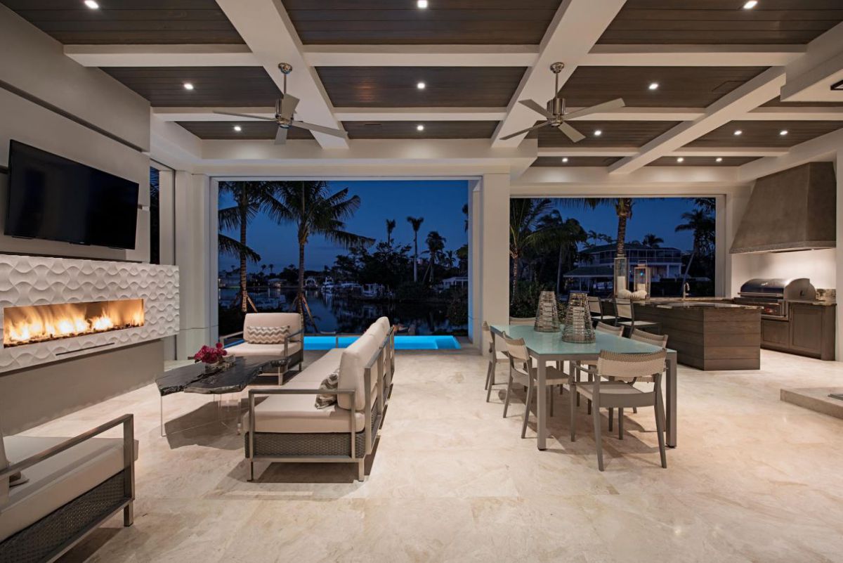 High-resolution real photograph of a modern covered outdoor living area with white coffer beams and dark wood ceiling panels