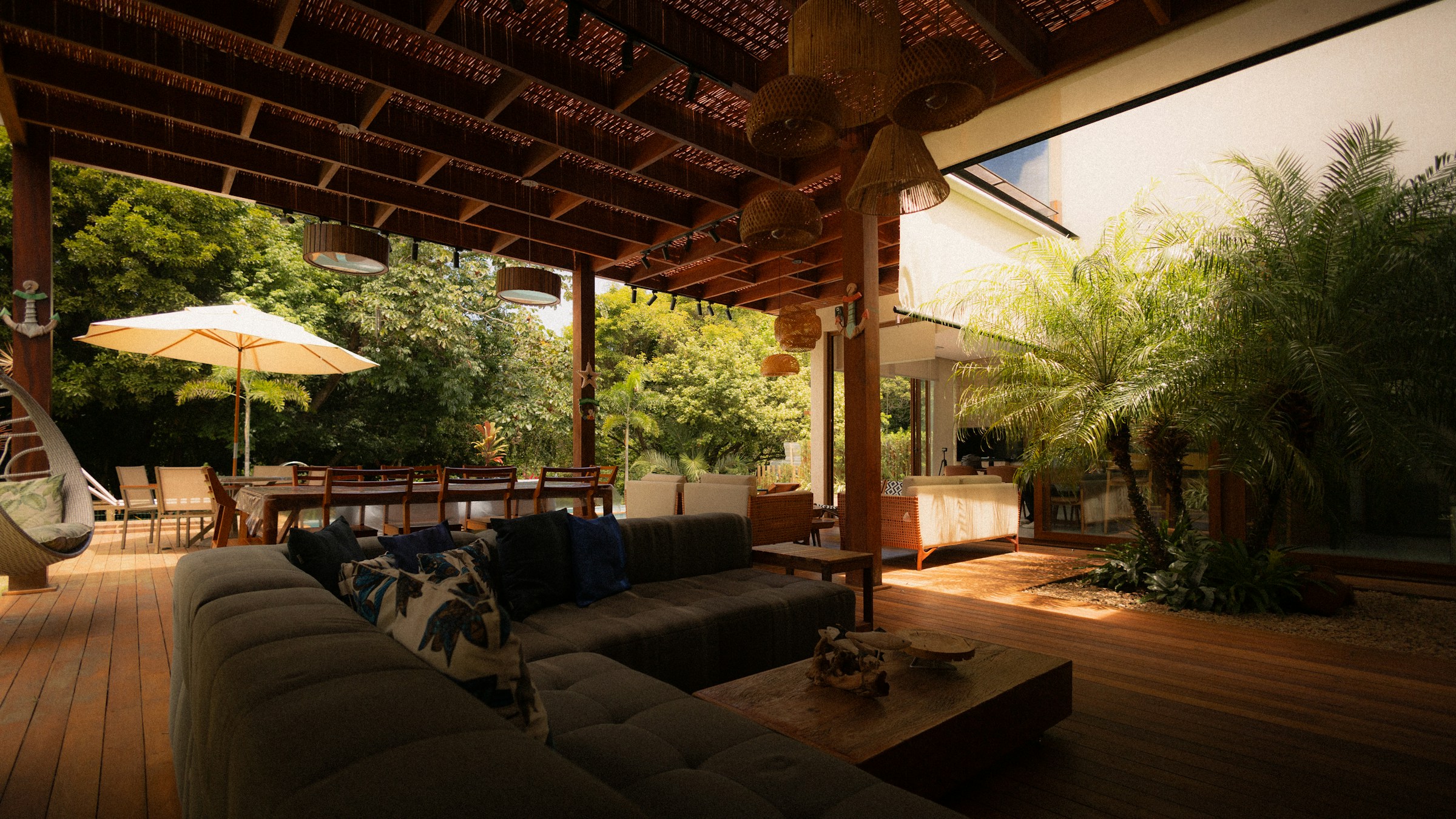 High-resolution real photograph of a luxury covered hardwood deck with timber framing, dining, and lounge areas