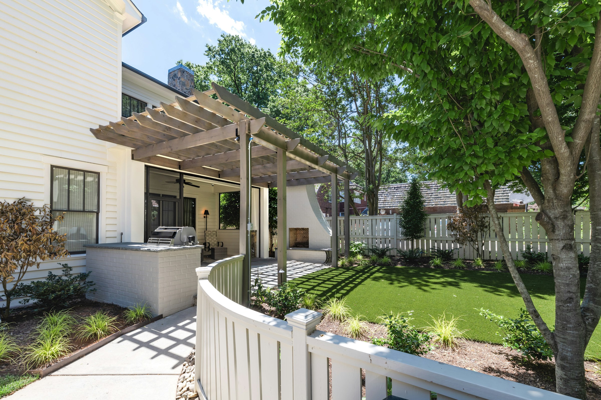 High-resolution real photograph of a modern timber pergola with an outdoor kitchen and custom white railing