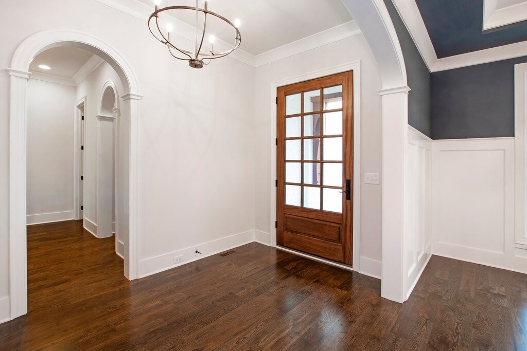 Real interior photograph of tall white-trimmed arched openings in a foyer